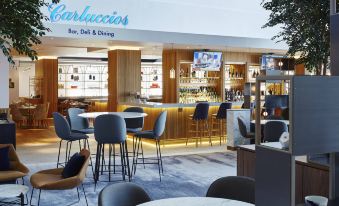 a modern bar with a blue and white color scheme , featuring various bottles and glasses on display at London Heathrow Marriott Hotel