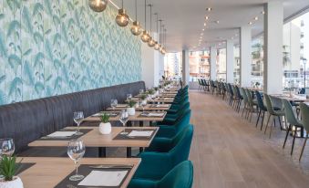 a long dining table with blue chairs and green upholstered chairs is set up in a modern restaurant at Occidental Fuengirola