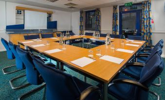 a conference room with a large wooden table surrounded by chairs , each chair having a chair around it at Holiday Inn Express Droitwich Spa