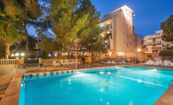 a large swimming pool with a hotel in the background and trees surrounding the area at Bluesea Costa Verde