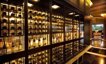 The room is equipped with shelves filled with numerous bottles, including wine glasses placed either in front or behind them at The Marmara Taksim