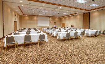 a large conference room with rows of tables and chairs , a projector screen , and a carpet at Hampton Inn Billings
