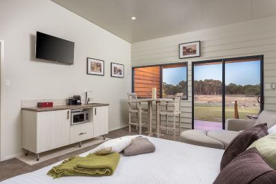 a modern bedroom with a bed , dining area , and sliding glass doors leading to an outdoor patio at The Swan Valley Retreat