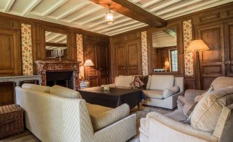 a cozy living room with wooden walls , a fireplace , and a large flat - screen tv mounted on the wall at The Good House