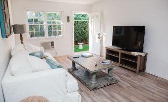 a living room with white walls , wooden floors , and furniture , including a couch , coffee table , and tv at Capri Southampton