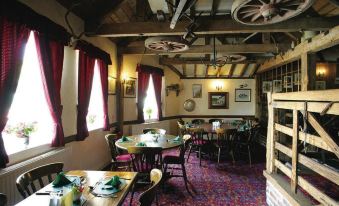 a restaurant with wooden tables and chairs , red curtains , and a carpeted floor , decorated with various items such as wine bottles , books at Malt House