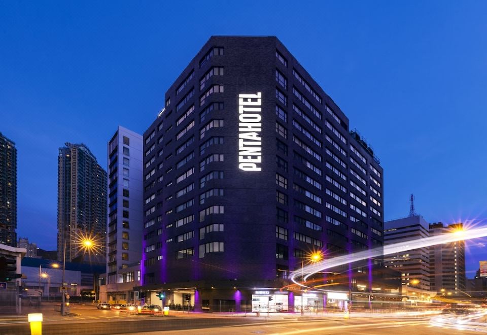 "At night, an illuminated skyscraper stands in front of a building with the word ""hotel"" on it" at Pentahotel Hong Kong, Tuen Mun