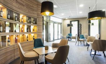 a modern lounge area with wooden walls , pendant lights , and various seating arrangements , including couches and chairs at Hôtel Mercure Libourne Saint-Émilion