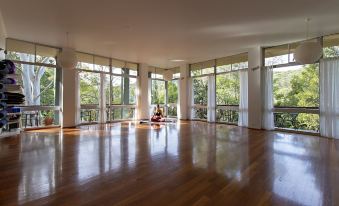 a large , empty room with wooden floors and windows , offering a view of trees outside at Heart & Soul Retreats