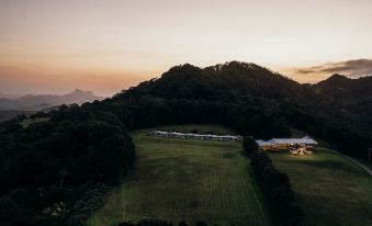 a beautiful sunset view over a mountainous landscape , with a green field and trees in the foreground at Ardeena