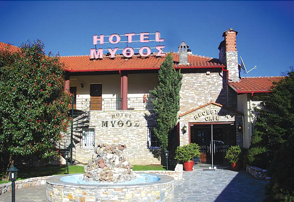 the hotel myyhox , a large building with a red roof and a fountain in front of it at Mythos