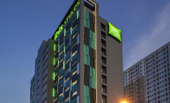 "a modern hotel building with a green and white sign that reads "" ibis styles "" in front of a blue sky" at Ibis Styles Bekasi Jatibening