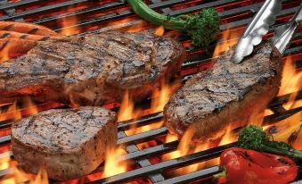 a group of grilled steak on a charcoal grill , accompanied by various vegetables and a fork at Great Wolf Lodge Grapevine