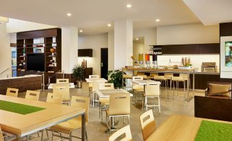a modern , well - lit restaurant with wooden tables and chairs , large windows , and a kitchen area at Element Fargo
