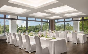 a well - decorated banquet hall with several white tables and chairs arranged for a formal event at Izu Marriott Hotel Shuzenji