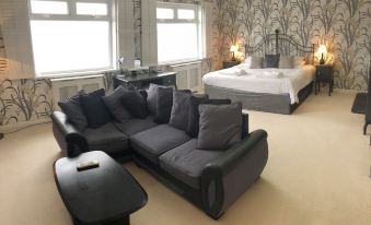 a modern living room with a black couch , white bed , and large windows , providing ample natural light at The Moorland Hotel