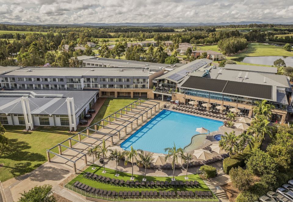 An aerial view showcases a hotel or resort with a spacious swimming pool and adjacent buildings at Rydges Resort Hunter Valley, an EVT hotel