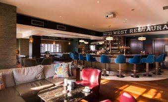 a modern bar area with various seating options , including couches , chairs , and a dining table at The Twelve Hotel