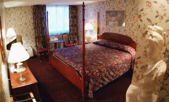 a large bed with a floral comforter is in a room with a wooden headboard and a desk at Best Western the Inn at Ramsey