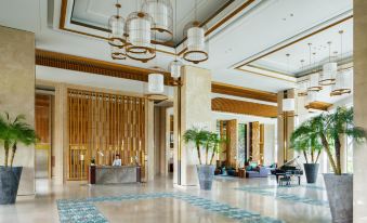 a grand hotel lobby with marble floors , wooden columns , and chandeliers , as well as a reception desk at Movenpick Resort Cam Ranh