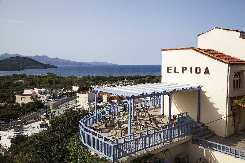 a balcony overlooking the ocean , with a dining table and chairs set up for a meal at Elpida Village