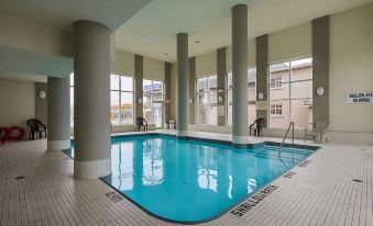 a large , empty swimming pool with a few people in the background and large windows at Comfort Hotel