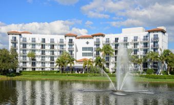 a large white building with a fountain in front of it , surrounded by green grass and trees at Inn at Pelican Bay