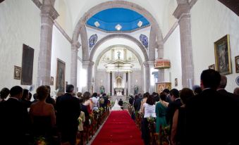 a wedding ceremony in a church with a bride and groom standing at the altar , surrounded by an audience at Hacienda San Gabriel de las Palmas