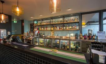 a well - stocked bar with numerous bottles and glasses , creating a lively atmosphere in a pub at Alpha Hotel Eastern Creek