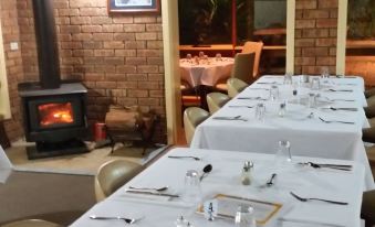 a dining room with tables set for a meal , and a fireplace in the background at Toora Lodge Motel