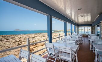 an outdoor dining area overlooking the ocean , with tables and chairs set up for a meal at Murdeira Village Resort