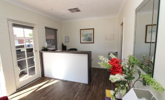 a small office space with a wooden floor , a white reception desk , and several potted plants at Mildura Riverview Motel