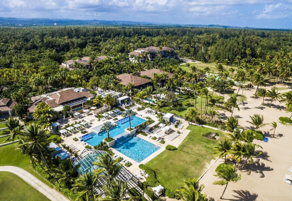 an aerial view of a resort with a pool surrounded by palm trees and grass at The St. Regis Bahia Beach Resort, Puerto Rico