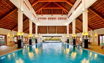 an indoor swimming pool surrounded by a building , with a large glass window providing ample natural light at Emeralda Resort Ninh Binh