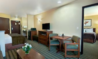 a hotel room with a bed , desk , chairs , and a tv . also a bathroom visible in the room at Oxford Suites Pendleton
