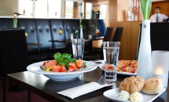 a dining table with a plate of salad and a plate of bread on it , along with two glasses of water at Hotel am Rhein