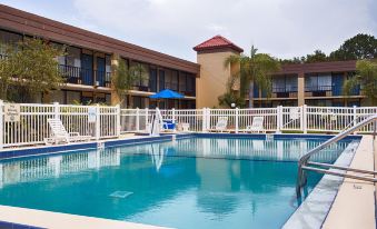 a hotel with a swimming pool surrounded by buildings , and a white fence surrounding the pool area at Ramada by Wyndham Cocoa