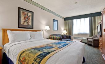 a hotel room with a large bed , two nightstands , and a chair , all decorated in white and blue colors at Best Western Plus Barclay Hotel