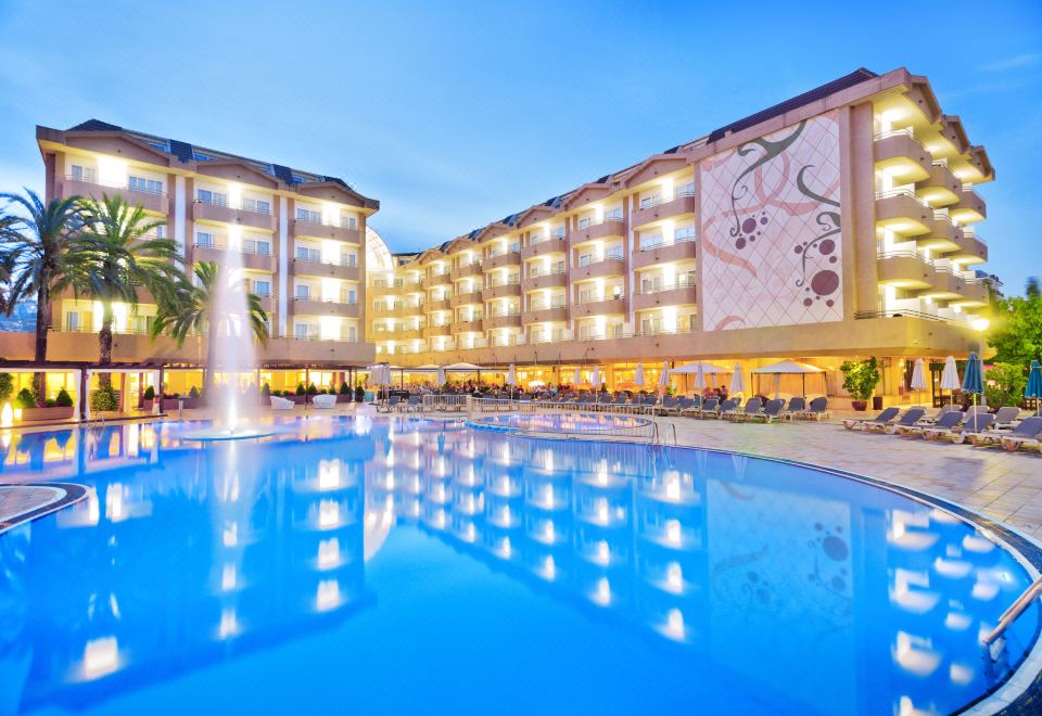 a large hotel with a swimming pool surrounded by lounge chairs and umbrellas , creating a relaxing atmosphere at Alegria Florida Park