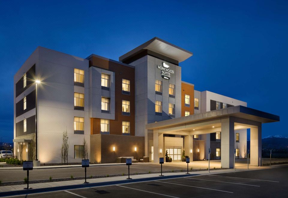 "a modern hotel building with the name "" holiday inn express "" lit up at night , surrounded by trees and cars parked on the street" at Homewood Suites by Hilton Salt Lake City Draper