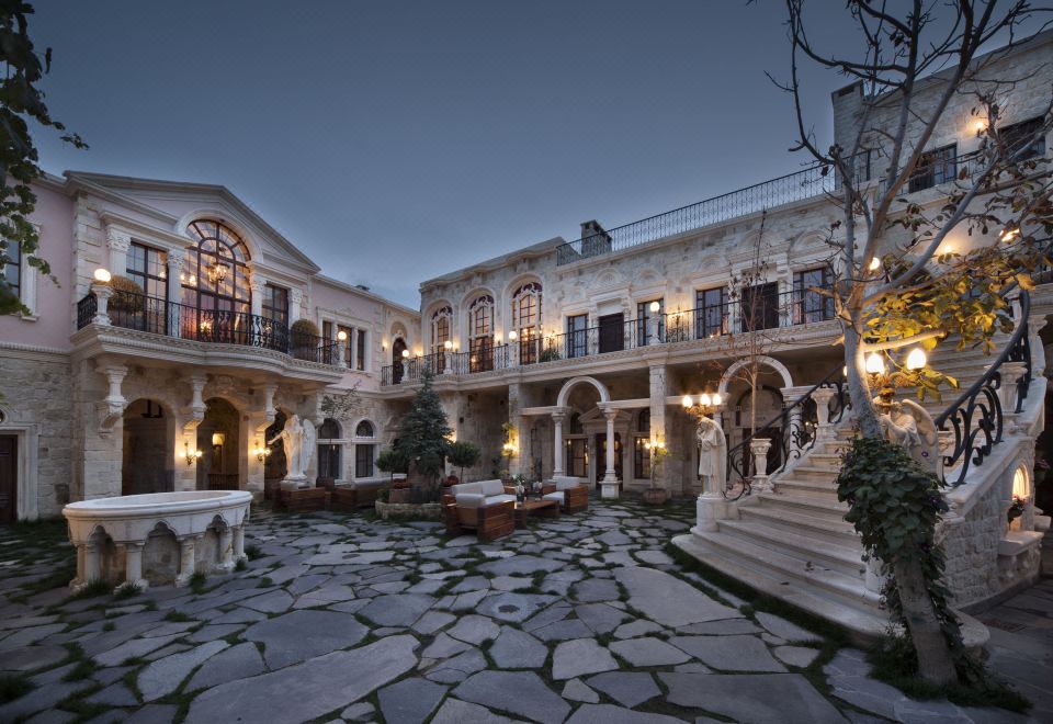 a grand , stone - paved courtyard with multiple levels of buildings and balconies , lit by street lights at night at Sacred House