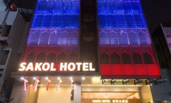 "a building with a blue and purple neon sign that says "" sakol hotel "" in front of it" at Sakol Hotel