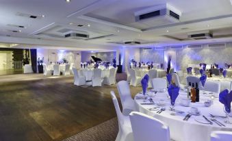 a large , well - decorated banquet hall with multiple dining tables and chairs set up for an event at DoubleTree by Hilton Bristol South - Cadbury House