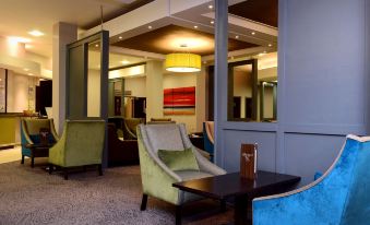 a modern lounge area with various seating options , including couches and chairs , as well as a coffee table at Holiday Inn Telford - Ironbridge