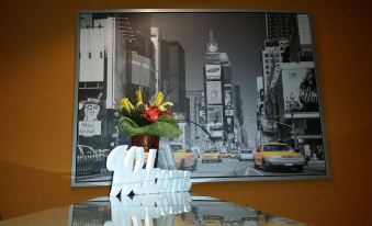 a city street scene with a large picture of the times square in new york city behind it , along with a white vase filled with flowers on at Hotel Aurora