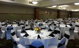 a large dining room with white tablecloths and black chairs , ready for a formal event at Casino Queen Hotel