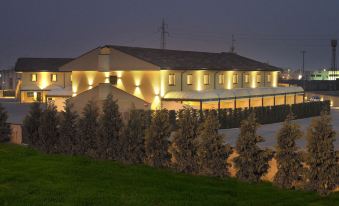 a large white building with multiple lights illuminating the exterior , surrounded by trees and grass at night at Hotel Nord