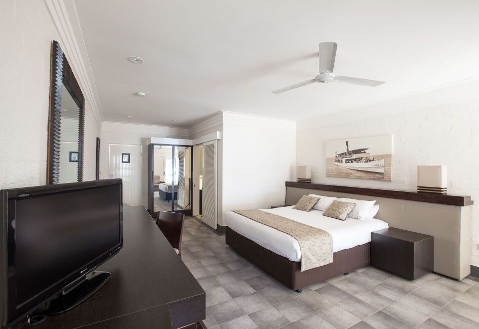 a modern hotel room with a king - sized bed , a flat - screen tv , and a desk area at Karma Rottnest