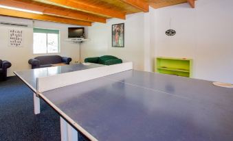 a ping pong table is set up in a room with wooden beams and white walls at Shepparton Holiday Park and Village
