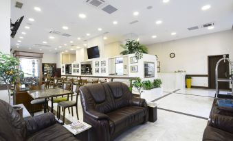 a modern living room with a brown leather couch , a dining table , and several chairs arranged around it at Citrus Hotel